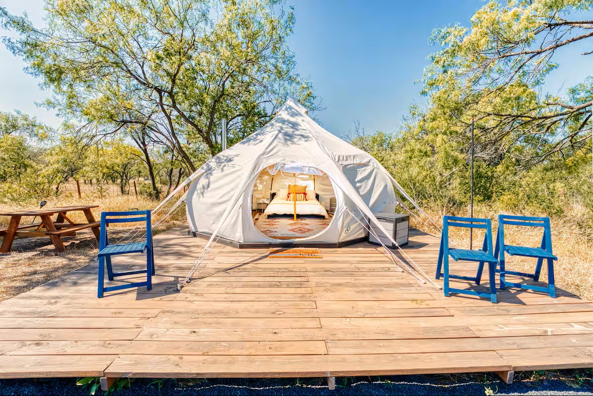 16107 Fagerquist Road Del Valle, TX 78617 - Photo 16 of 17 Glamping escape with a welcoming tent, outdoor seating, and a picnic area under sun-dappled trees.