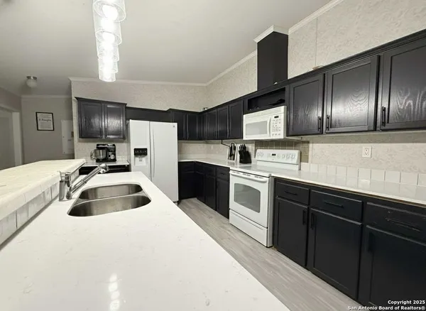 a kitchen with granite countertop a sink and refrigerator