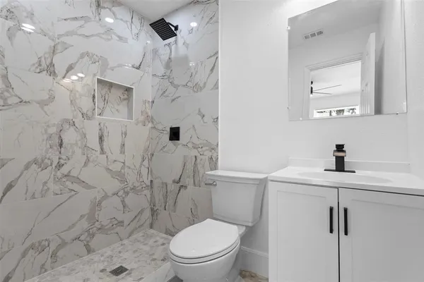 a bathroom with a toilet sink vanity and shower