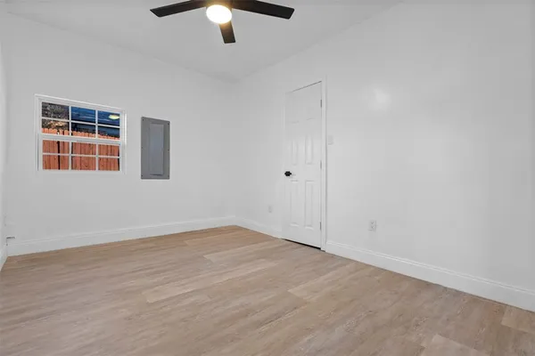 an empty room with wooden floor chandelier fan and windows