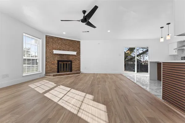 an empty room with wooden floor fireplace and windows