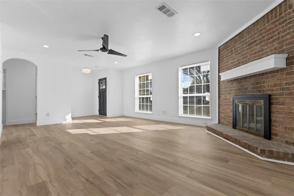 an empty room with wooden floor fireplace and windows