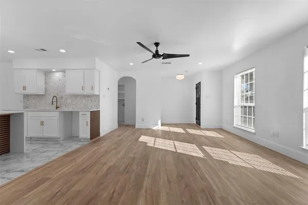 a view of an empty room with a kitchen and a window