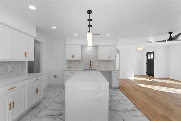 a large white kitchen with kitchen island a sink stainless steel appliances and cabinets