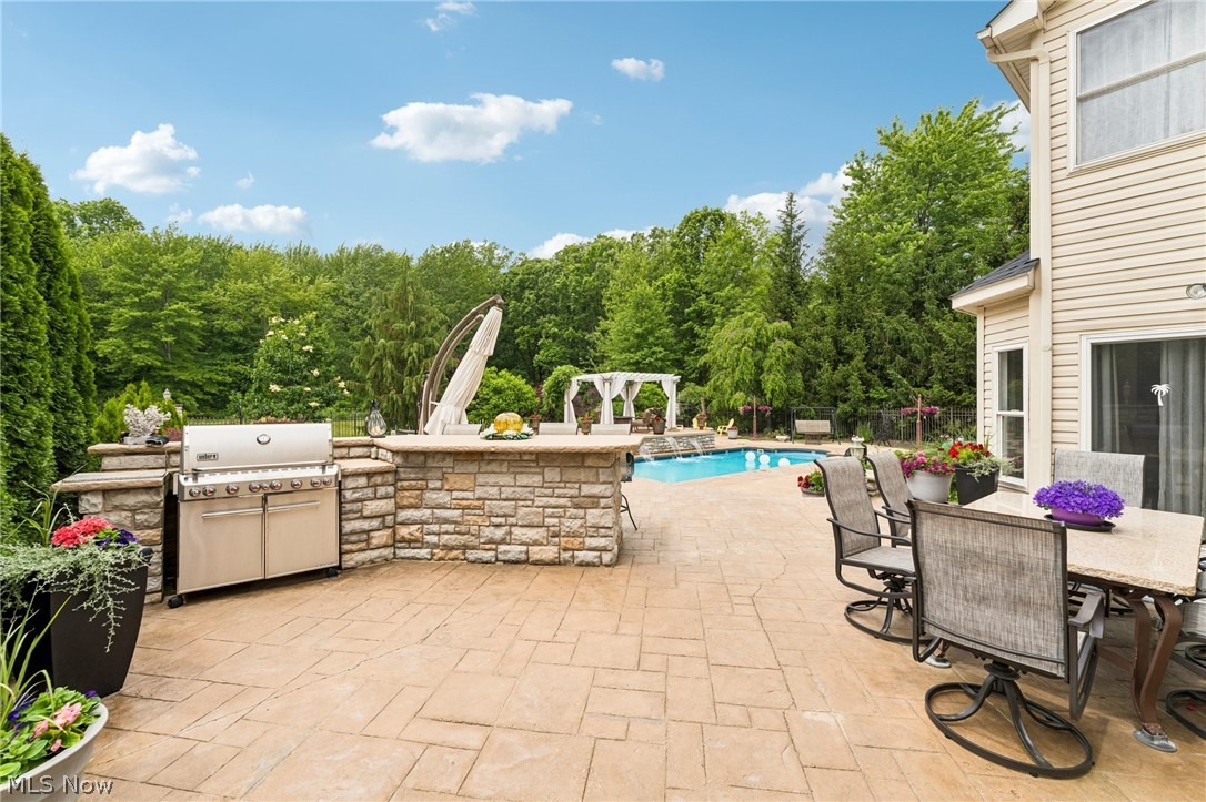 8874 Sharp Road Olmsted Falls, OH 44138 - Photo 25 of 42 Expansive stamped concrete patio featuring an outdoor kitchen with stone veneer base and built-in grill