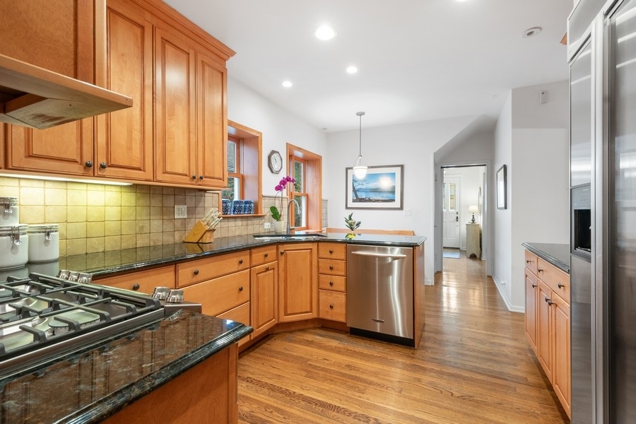 606 Barton Avenue Evanston, IL 60202 - Photo 7 of 27 a kitchen with stainless steel appliances granite countertop a refrigerator a sink dishwasher a stove and white countertops with wooden floor
