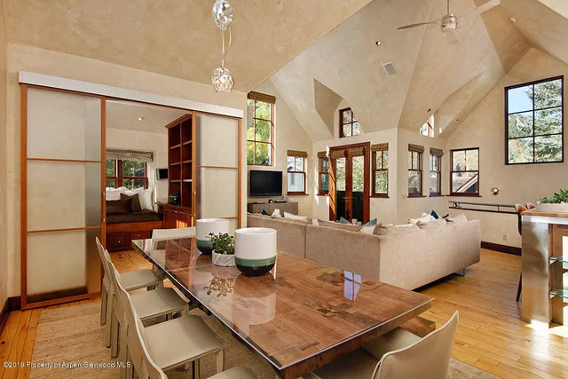 a living room with dining table and a refrigerator