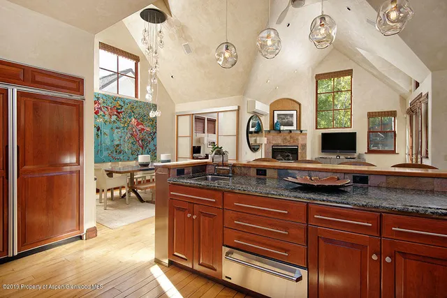 a dining hall with granite countertop a refrigerator a stove a dining table and chairs with wooden floor