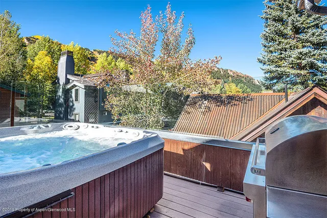 a view of a house with wooden deck and floor to ceiling window