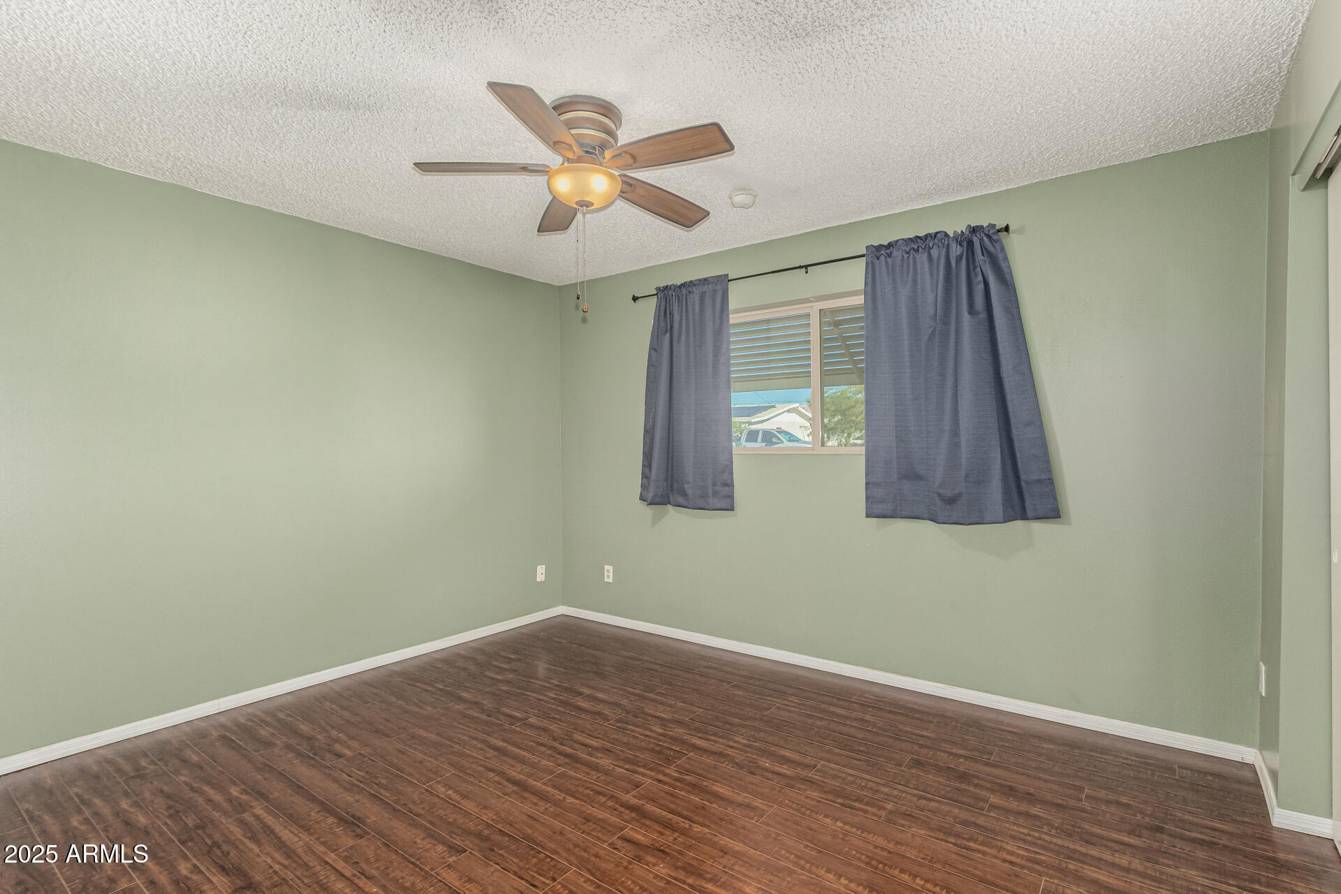 1206 South Grand Drive Apache Junction, AZ 85120 - Photo 14 of 26 an empty room with wooden floor fan and windows