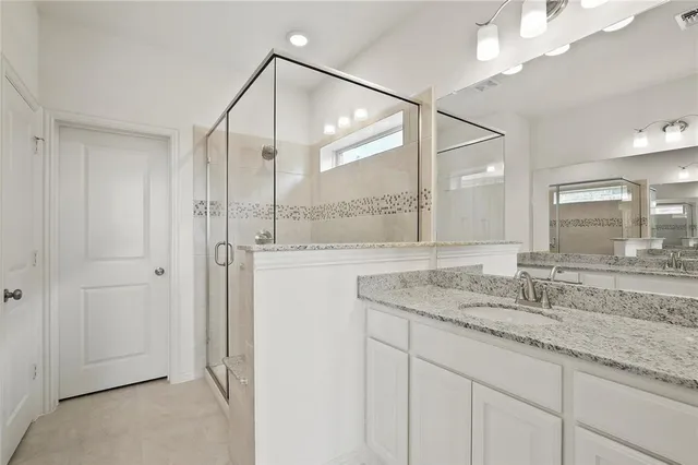 a bathroom with a granite countertop sink a mirror and a shower