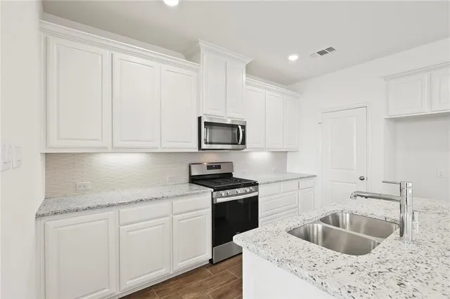 a kitchen with granite countertop white cabinets sink and stainless steel appliances