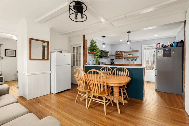 a dining room with furniture a kitchen wooden floor and a refrigerator