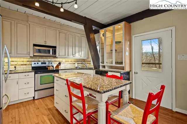 a kitchen with a stove a sink dishwasher and a refrigerator with wooden floor