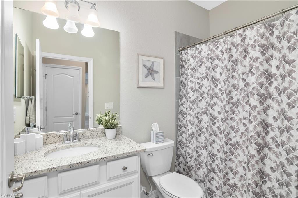 19828 The Pl Boulevard Estero, FL 33928 - Photo 18 of 37 a bathroom with a granite countertop toilet sink and mirror