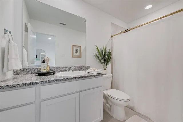 a bathroom with a granite countertop sink a toilet and a mirror