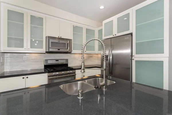 a kitchen with kitchen island a counter top space cabinets stainless steel appliances and a window