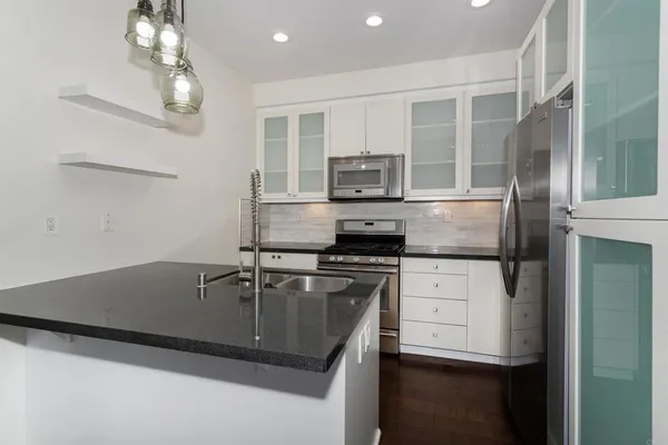 a kitchen with stainless steel appliances granite countertop a sink a stove and refrigerator