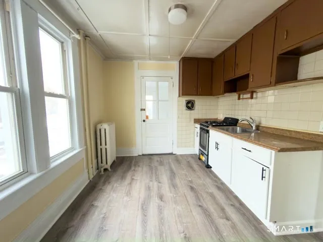 a kitchen with granite countertop a stove a sink dishwasher and a refrigerator with wooden floor