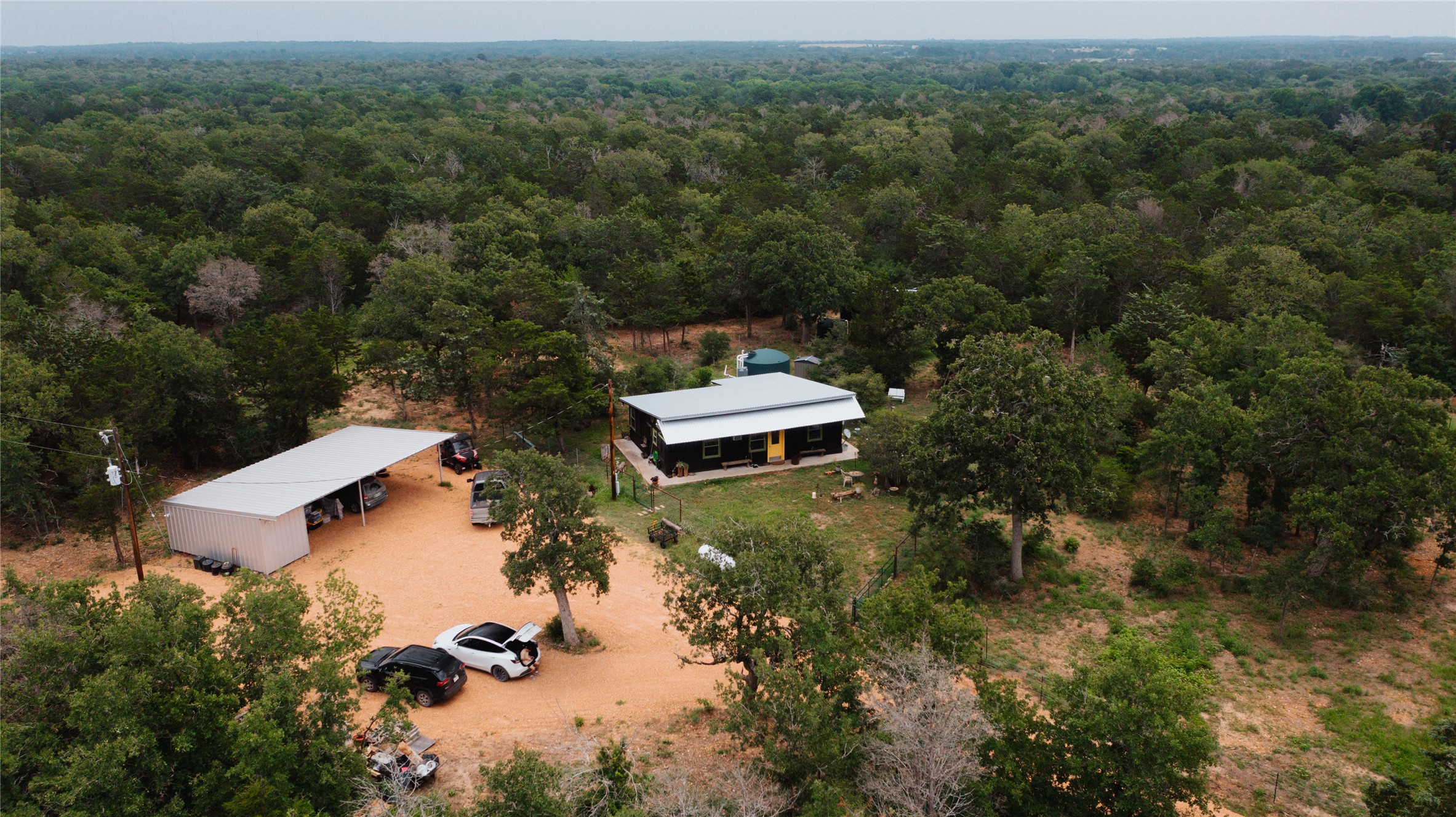 853 St Delight Road Paige, TX 78659 - Photo 2 of 39 View from above of property featuring a home, carport and heavily wooded area