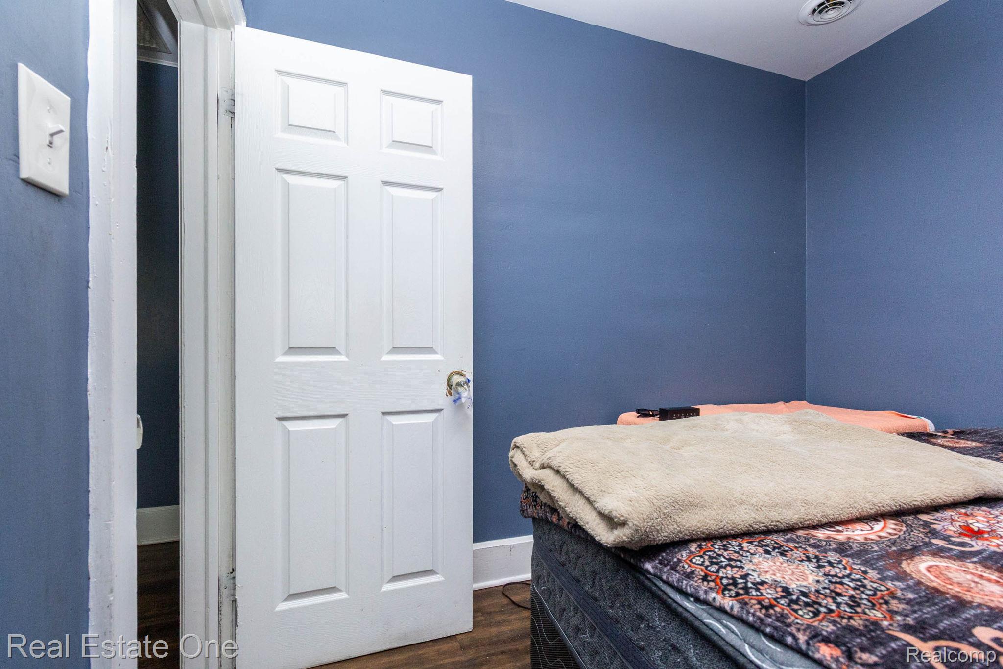 5485 Springwells Street Detroit, MI 48210 - Photo 33 of 47 Room featuring a six-panel interior door, blue painted walls, wood-finish flooring, and white trim