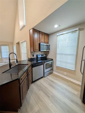 a kitchen with granite countertop a sink stainless steel appliances and cabinets