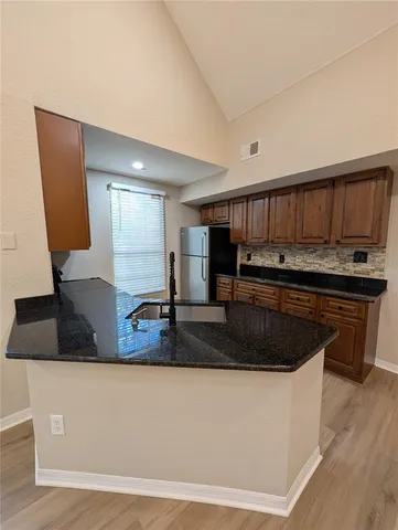 a kitchen with kitchen island granite countertop a sink a counter top space and cabinets