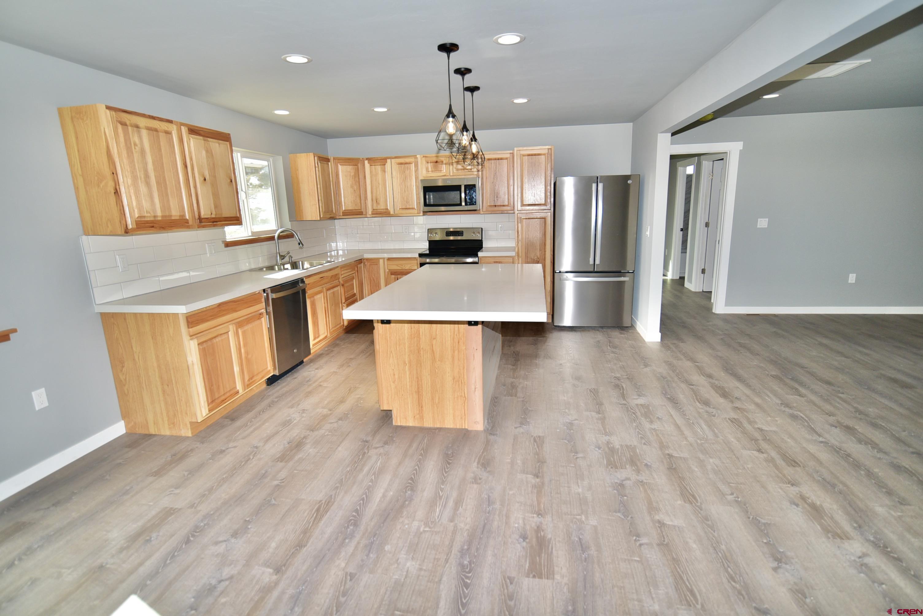 66462 Landfill Road Montrose, CO 81401 - Photo 11 of 30 a kitchen with stainless steel appliances granite countertop a stove a sink dishwasher and a refrigerator with wooden floor