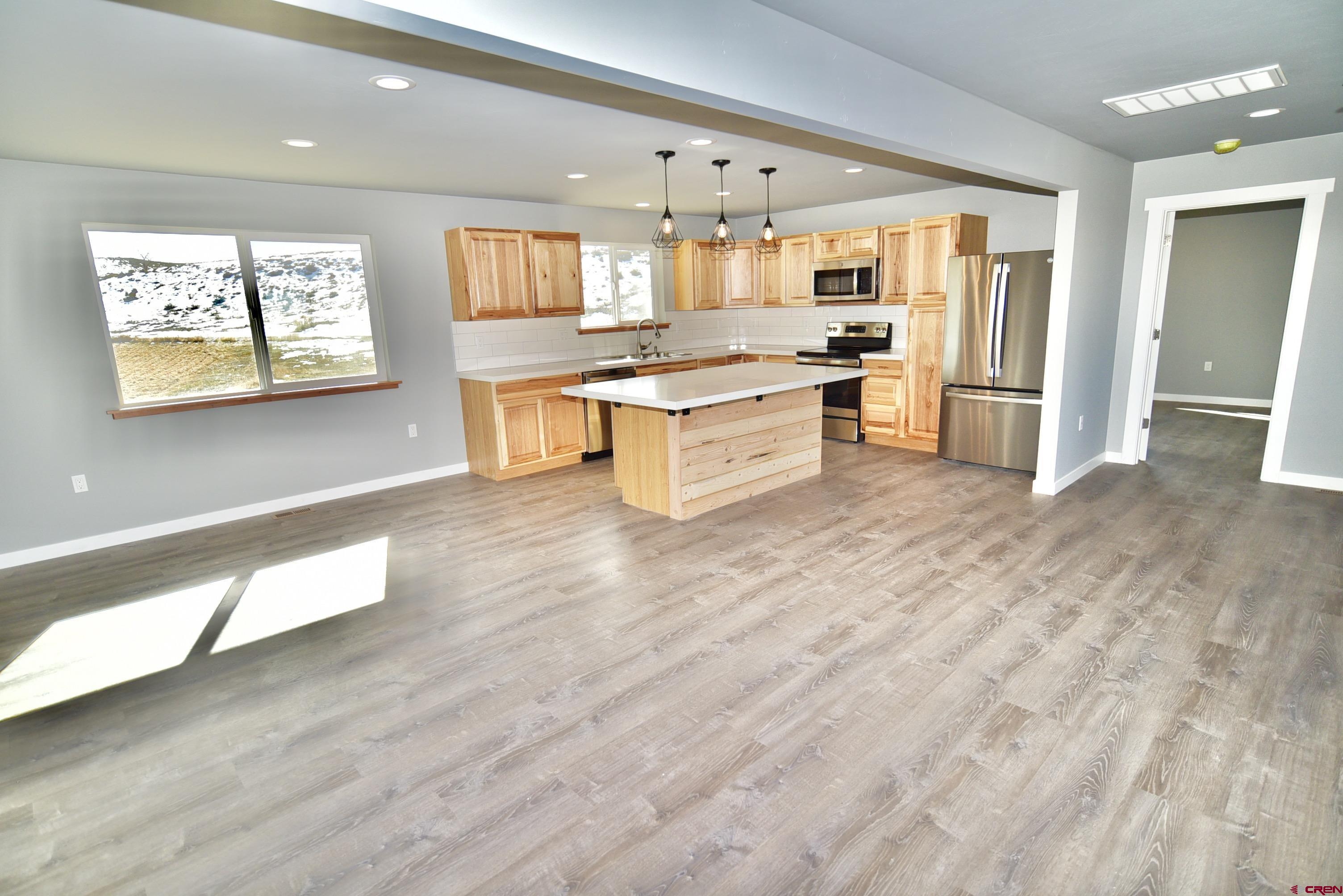66462 Landfill Road Montrose, CO 81401 - Photo 16 of 30 a large kitchen with stainless steel appliances kitchen island a large counter top and a wooden floors