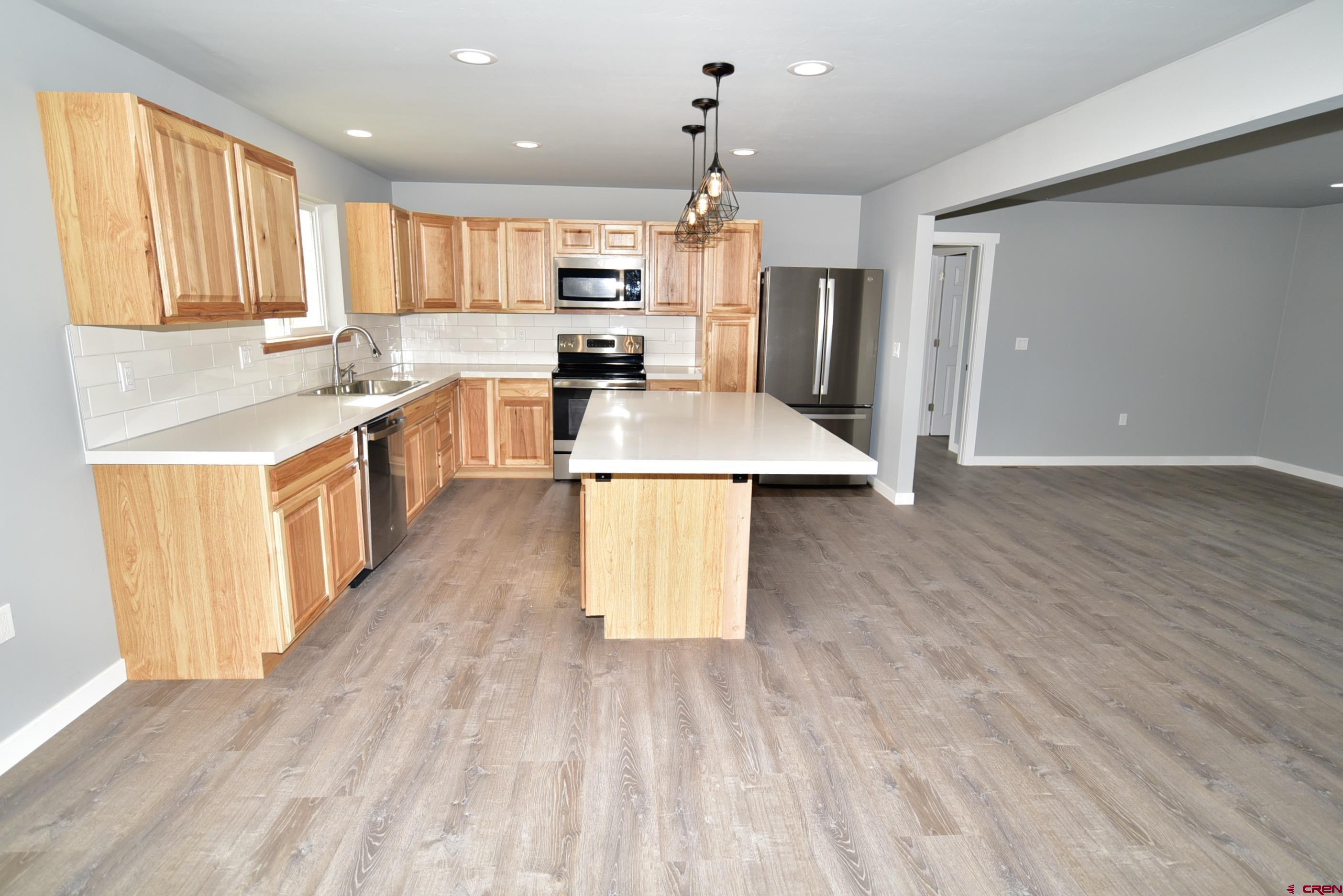 66462 Landfill Road Montrose, CO 81401 - Photo 17 of 30 a kitchen with stainless steel appliances a stove top oven a sink dishwasher and a refrigerator with wooden floor
