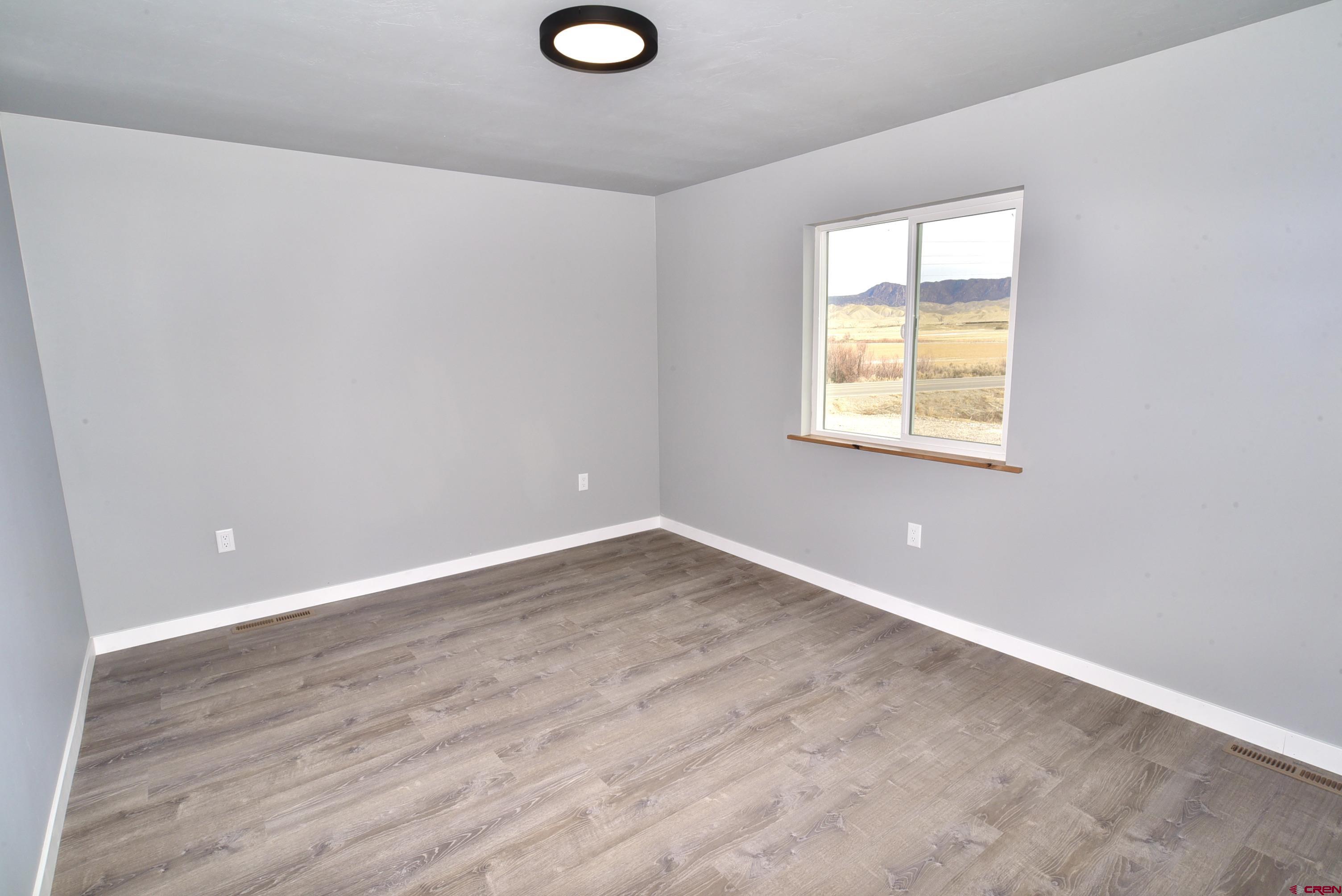 66462 Landfill Road Montrose, CO 81401 - Photo 23 of 30 an empty room with wooden floor and windows