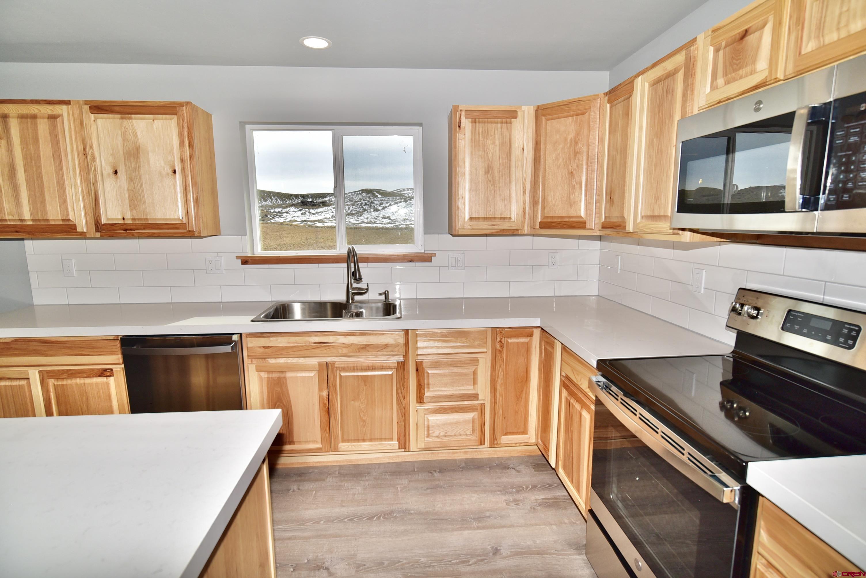 66462 Landfill Road Montrose, CO 81401 - Photo 9 of 30 a kitchen with stainless steel appliances granite countertop a stove a sink and a microwave