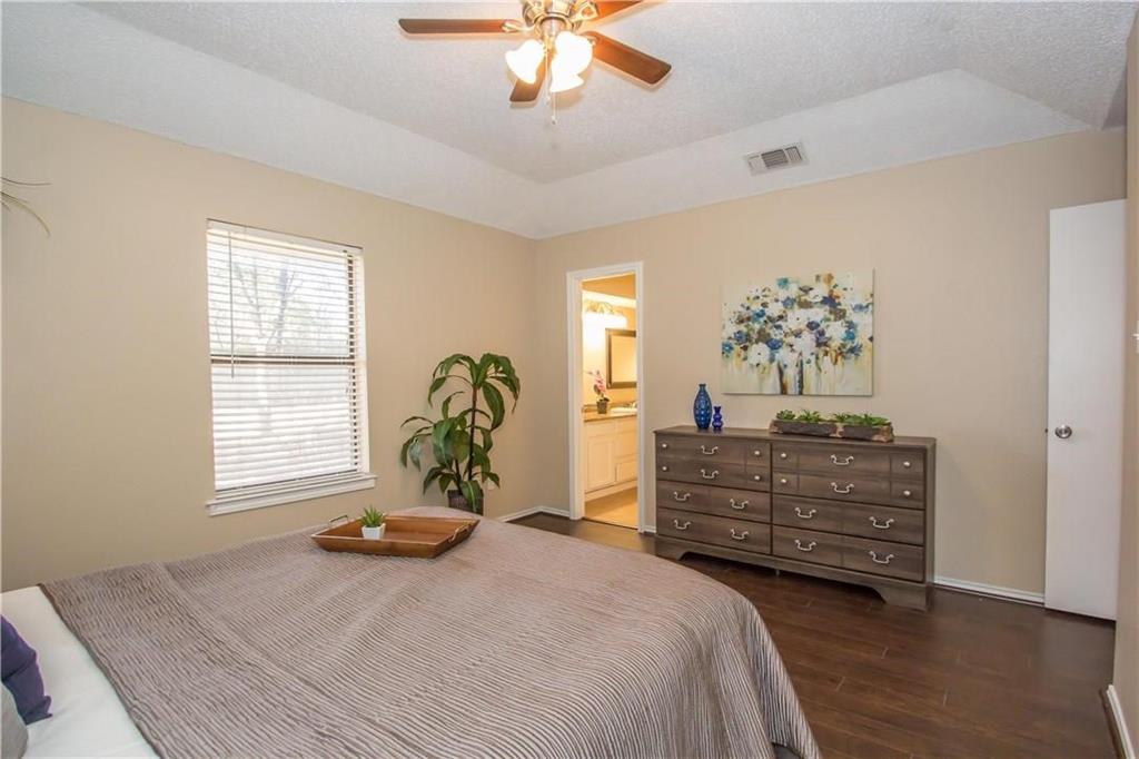 2405 Cranberry Lane Euless, TX 76039 - Photo 11 of 19 Bedroom featuring dark wood finished floors, a textured ceiling, connected bathroom, and a ceiling fan