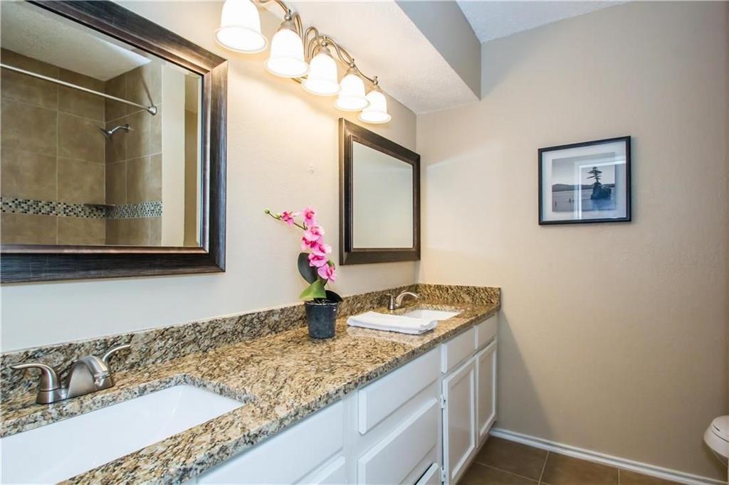 2405 Cranberry Lane Euless, TX 76039 - Photo 17 of 19 Bathroom with double vanity, dark tile patterned floors, and a shower