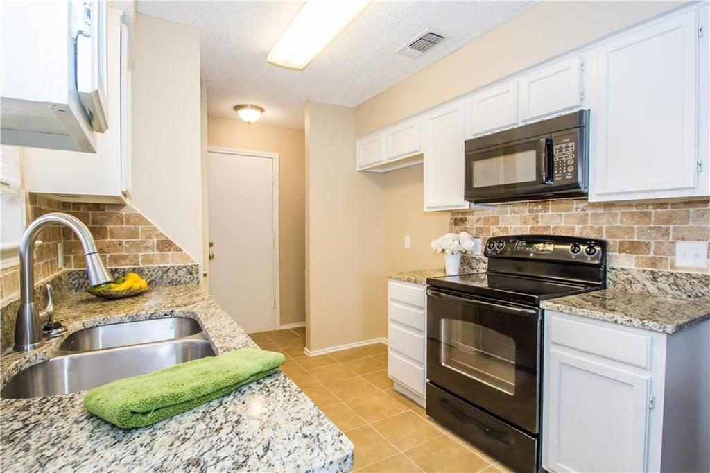 2405 Cranberry Lane Euless, TX 76039 - Photo 8 of 19 Kitchen with decorative backsplash, black appliances, light tile patterned flooring, white cabinets, and a textured ceiling