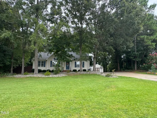 a view of a house with a big yard and large trees