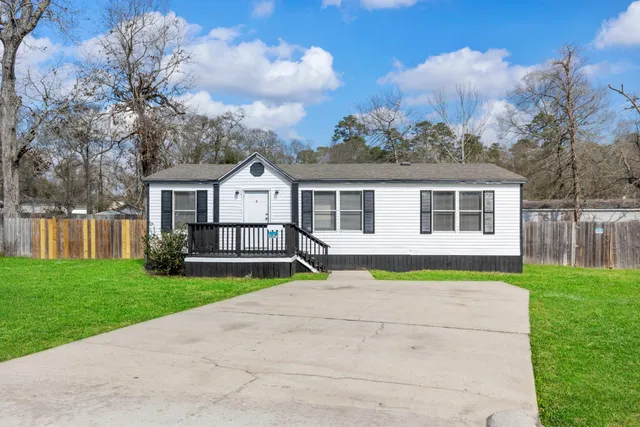 a view of a house with a yard and a large tree
