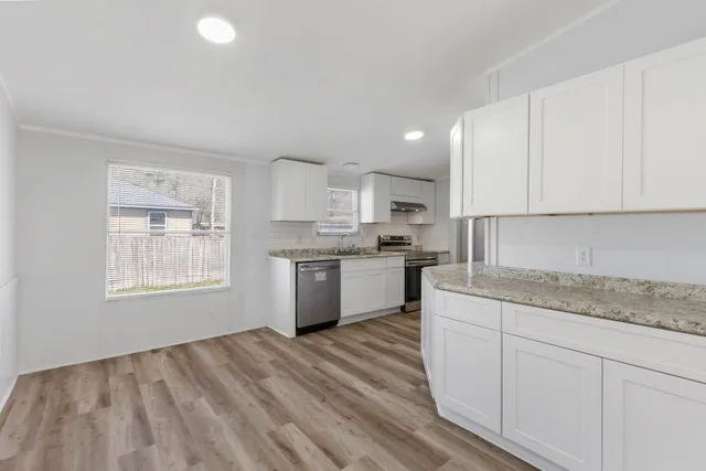 a kitchen with granite countertop white cabinets and white appliances