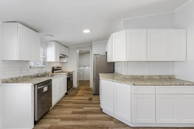 a large kitchen with stainless steel appliances granite countertop a stove and a white cabinets