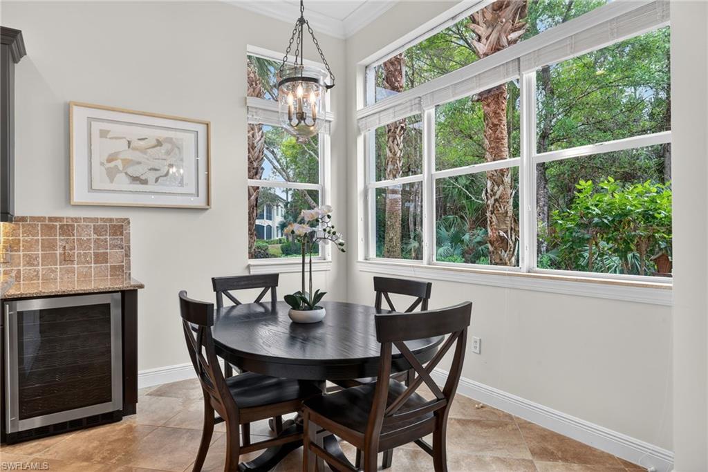 28540 Calabria Court, Unit 101 Naples, FL 34110 - Photo 12 of 41 Dining room with beverage cooler, crown molding, and a chandelier
