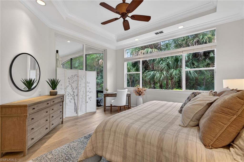 28540 Calabria Court, Unit 101 Naples, FL 34110 - Photo 16 of 41 Bedroom featuring light wood-style flooring, ceiling fan, recessed lighting, ornamental molding, and a tray ceiling