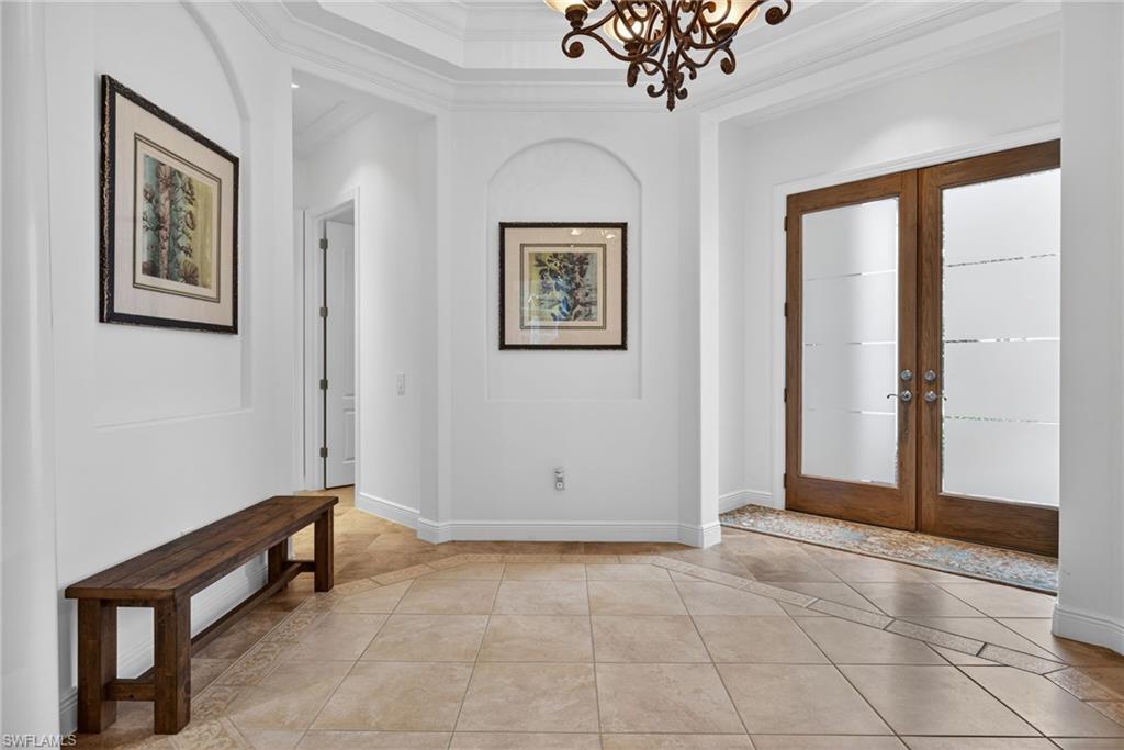 28540 Calabria Court, Unit 101 Naples, FL 34110 - Photo 2 of 41 Entryway with french doors, crown molding, light tile patterned floors, and inlaid floor details