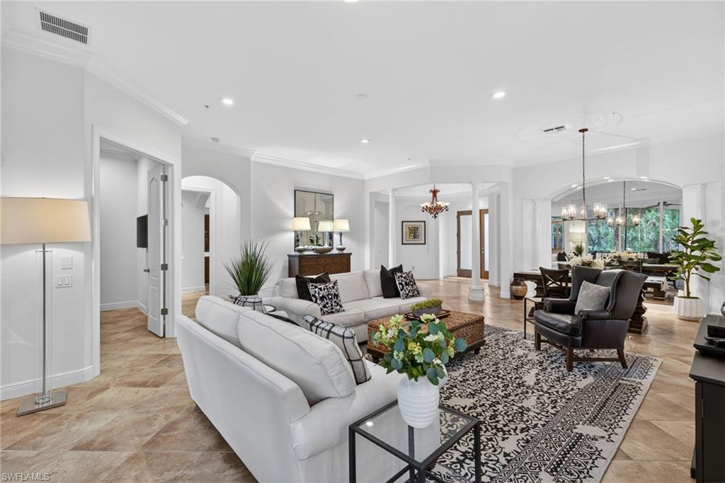 28540 Calabria Court, Unit 101 Naples, FL 34110 - Photo 3 of 41 Living room with arched walkways, decorative columns, a chandelier, recessed lighting, and ornamental molding