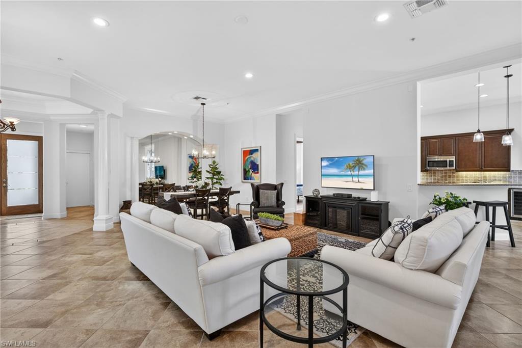 28540 Calabria Court, Unit 101 Naples, FL 34110 - Photo 6 of 41 Living area with ornamental molding, a chandelier, ornate columns, wine cooler, and recessed lighting
