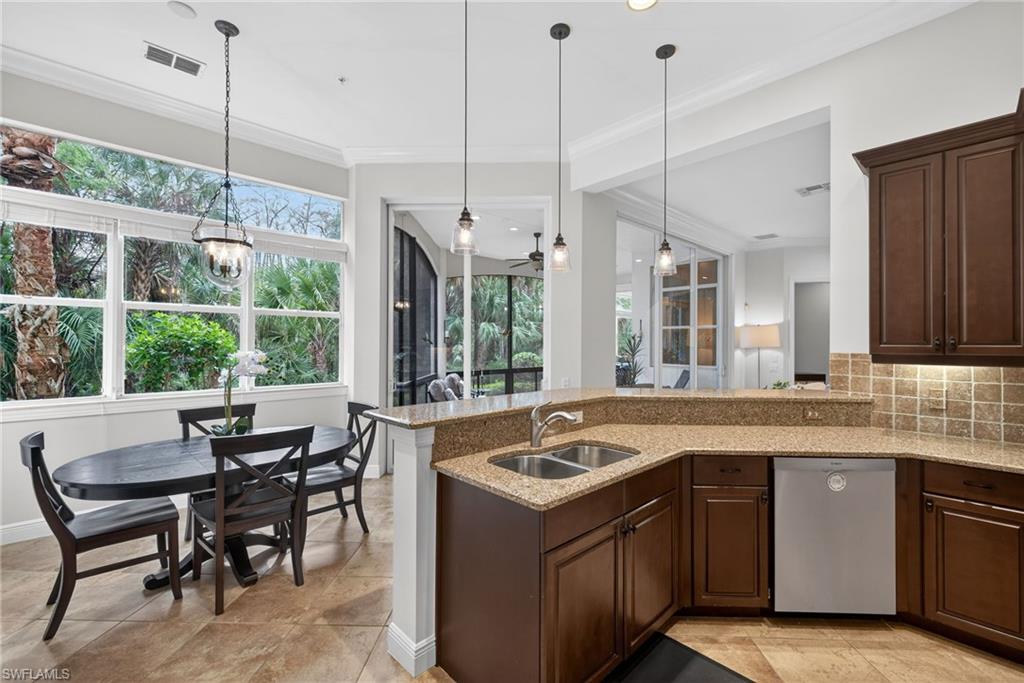 28540 Calabria Court, Unit 101 Naples, FL 34110 - Photo 10 of 41 Kitchen with dark brown cabinetry, light stone countertops, decorative light fixtures, stainless steel dishwasher, and decorative backsplash