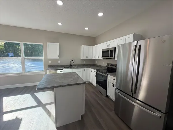 a kitchen with granite countertop stainless steel appliances cabinets a sink and a window