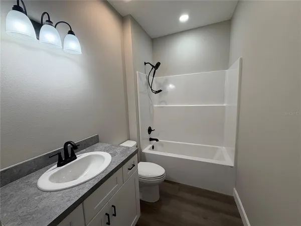 a bathroom with a granite countertop sink toilet a mirror and shower