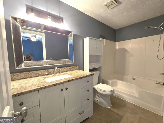 a bathroom with a granite countertop sink toilet and shower