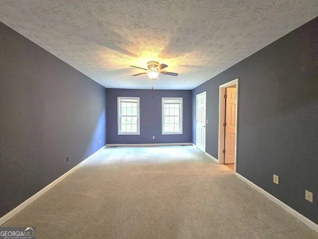a view of a big room with windows and chandelier fan