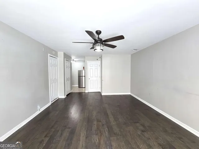 an empty room with wooden floor and ceiling fan